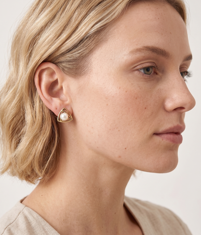 lumina pearl triangle stud earrings in yellow gold finish — model view